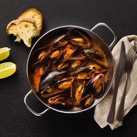freshly cooked mussels in a frying pan in tomato sauce. pepata d freshly cooked mussels in a frying pan in tomato sauce. pepata di cozze or mussels marinara. classic dish of mediterranean italian cuisine. on black background